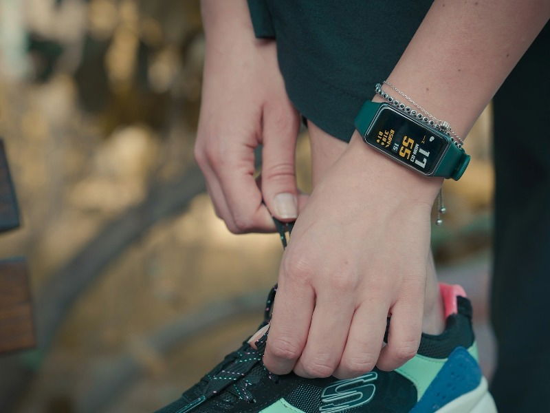 Person wearing a fitness band and tying their shoes