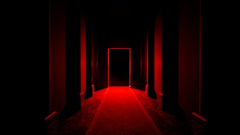 An image from the game Dark Deception, showing a dark hallway lit only in red.