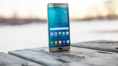 Samsung phone sitting on wood table.