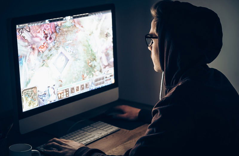 man in hood playing a game on screen