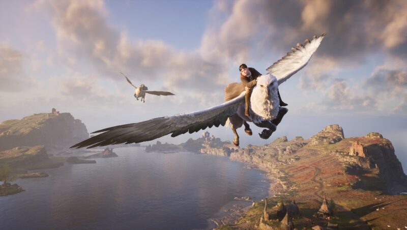 A screenshot of one of the best open-world games, Hogwarts Legacy, featuring two students flying in the sky riding a mythical white creature called a Hippogriff, over a lake and some landmasses.