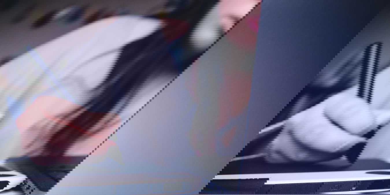 A photograph of a woman drawing on a computer tablet.