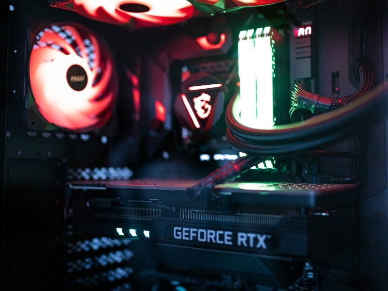 A gaming PC with a graphics card, RAM, and fans in RGB lighting