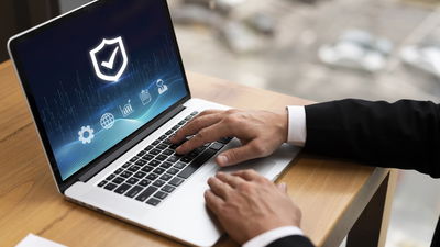 hands on a laptop with security check on the screen