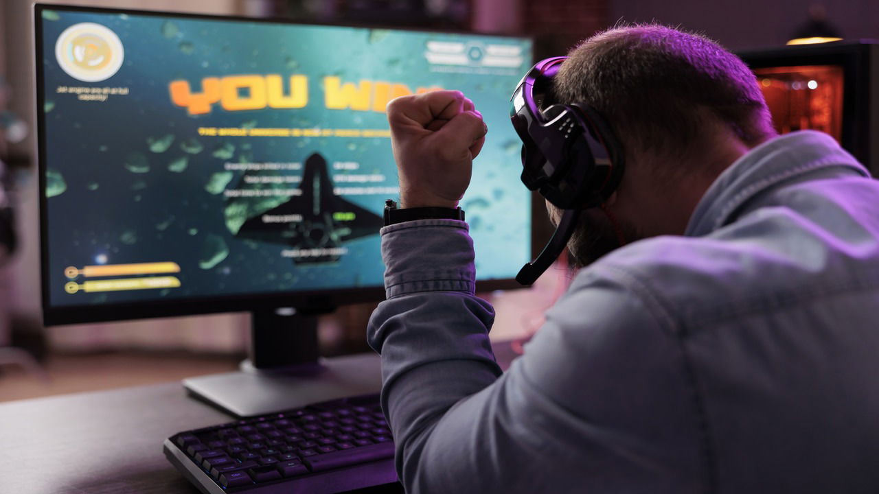 man celebrating his win in a video gme with win text on screen