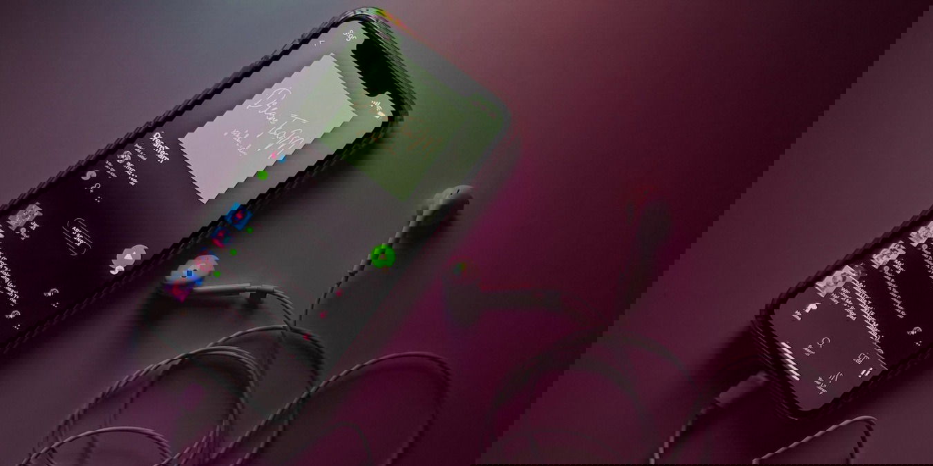 Spotify app on black smartphone with earphones on a desk